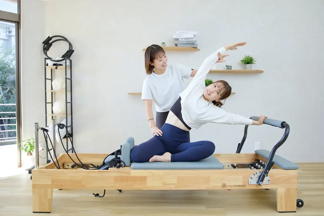 落ち着いた雰囲気のスタジオでレッスンを受ける女性とトレーナー（痛み・コリの改善）