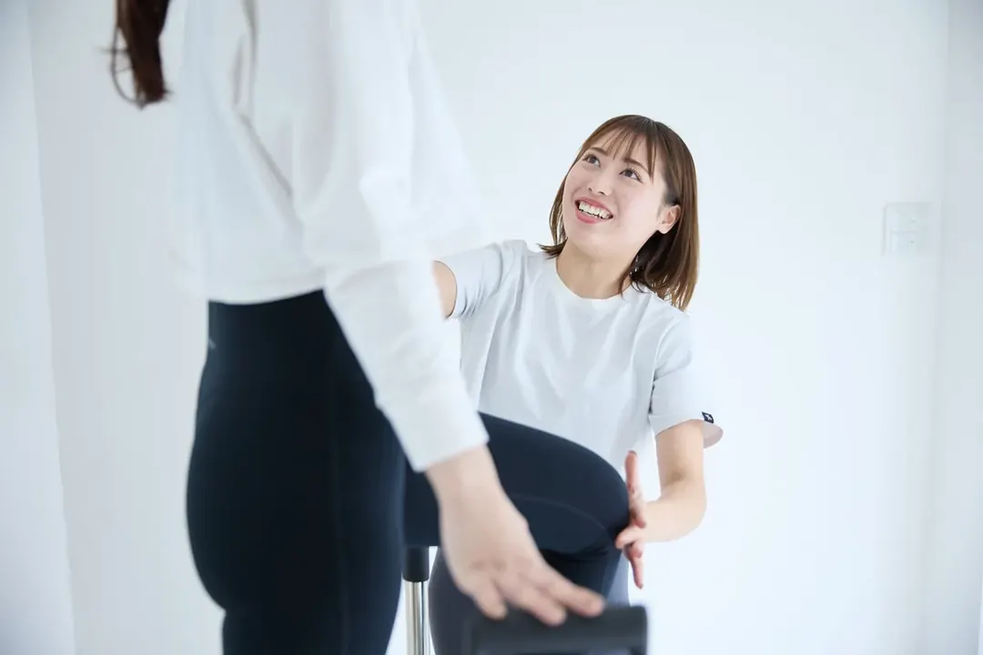 トレーナーに支えられながら行う下半身のエクササイズ（健康・体力向上）