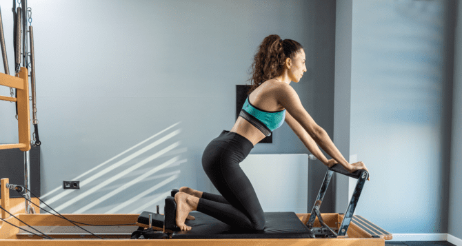 Woman wearing green bra top doing pilates