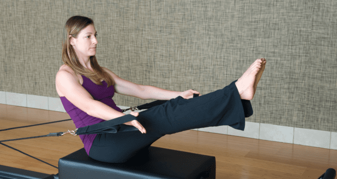 Woman wearing purple top doing pilates