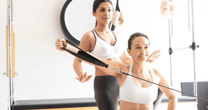 Woman and instructor receiving Pilates with a smile