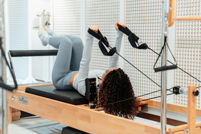 A woman training on a reformer in a supine position