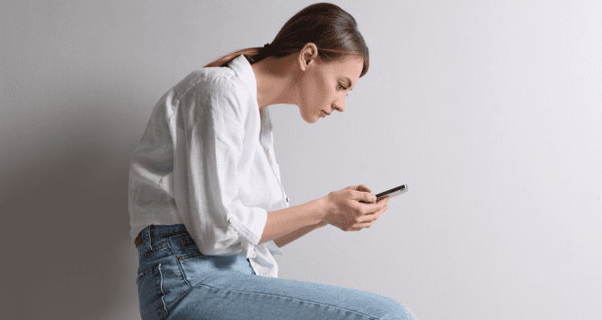 A woman with a hunched back looking at her smartphone.