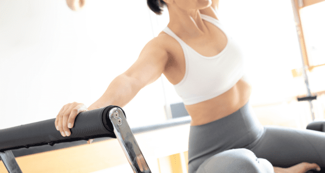 Woman in tank top doing reformer
