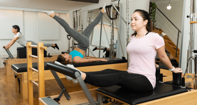 Three women training on the reformer.