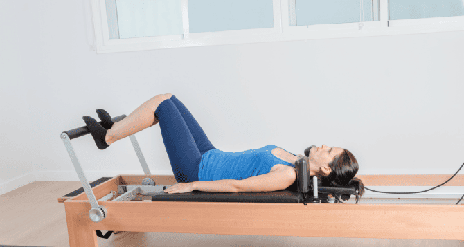 A woman exercising wearing blue Pilates wear