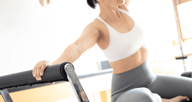 A woman wearing a bra top doing Pilates