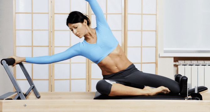 A woman doing lateral bending exercise with a reformer