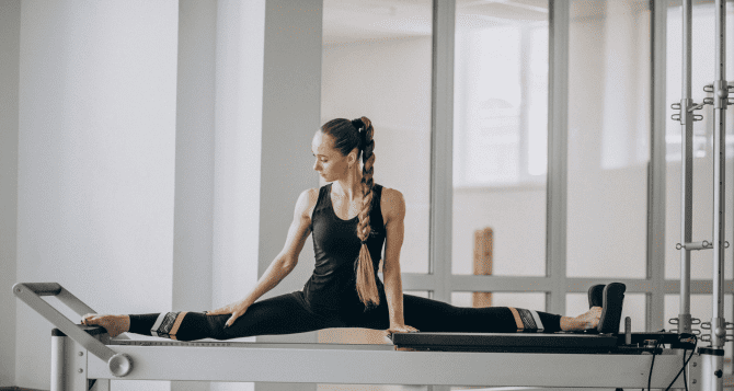 Woman doing splits on a reformer
