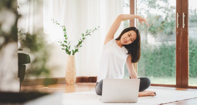 A woman stretching while looking at a computer