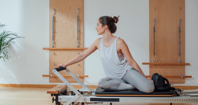 A woman sitting and using a reformer